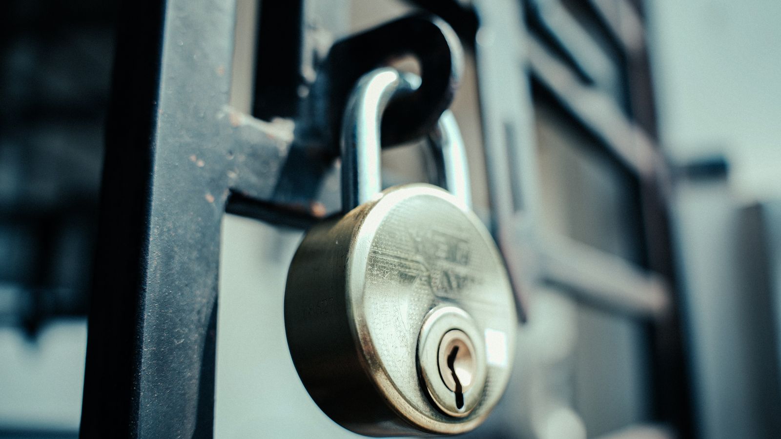 Cadenas métallique fermé accroché à une grille en fer sombre